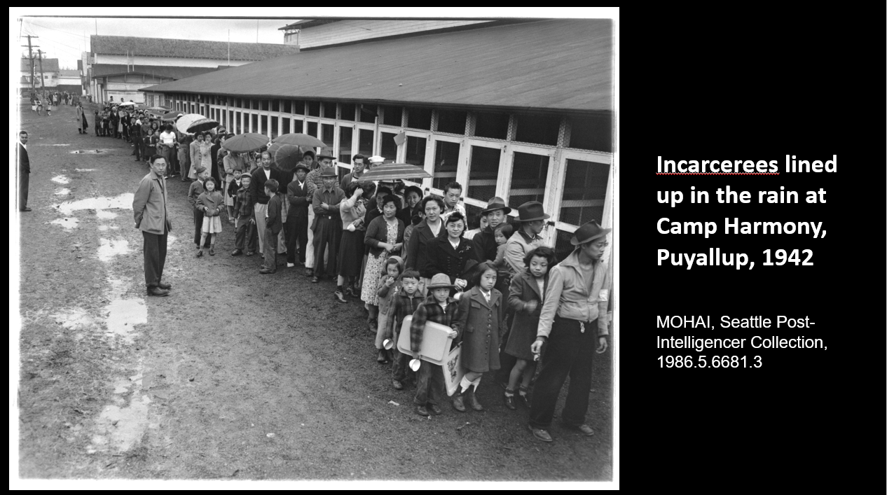 WWII Japanese American Incarcerees lined up in the rain at Camp Harmony, Puyallup, 1942   MOHAI, Seattle Post-Intelligencer Collection, 1986.5.6681.3